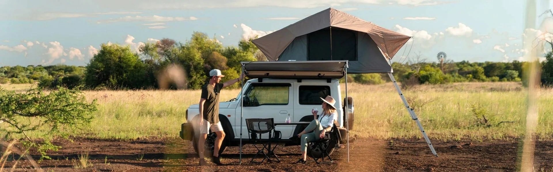 White Suzuki Jimny 3-door with a Front Runner rack, rooftop tent and awning at camp in the bushveld