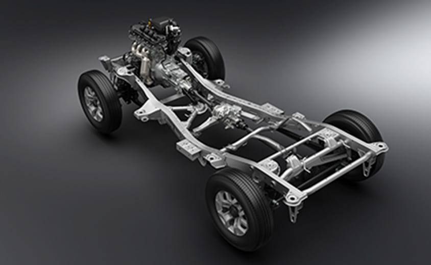 A studio image of a Suzuki Jimny with no body: the steel ladder frame, engine, gearbox and a solid axle at each end