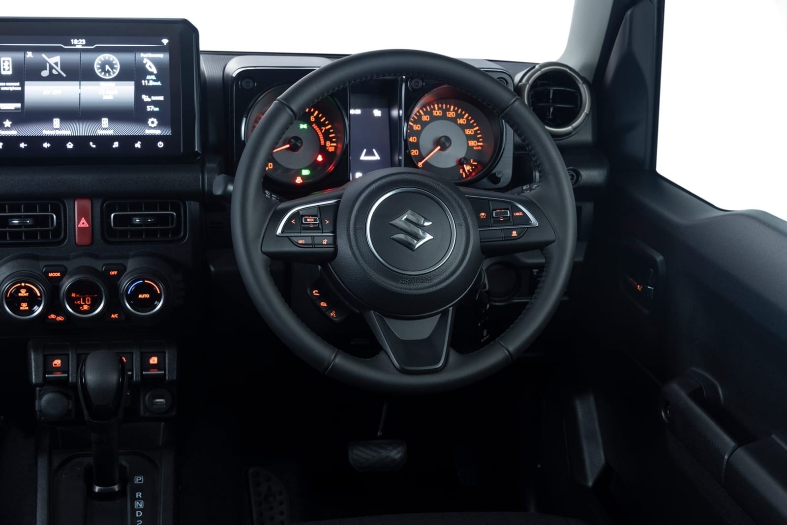 The driver's view of a Suzuki Jimny 3-door automatic, with buttons on the steering wheel, two round dials and a touch screen