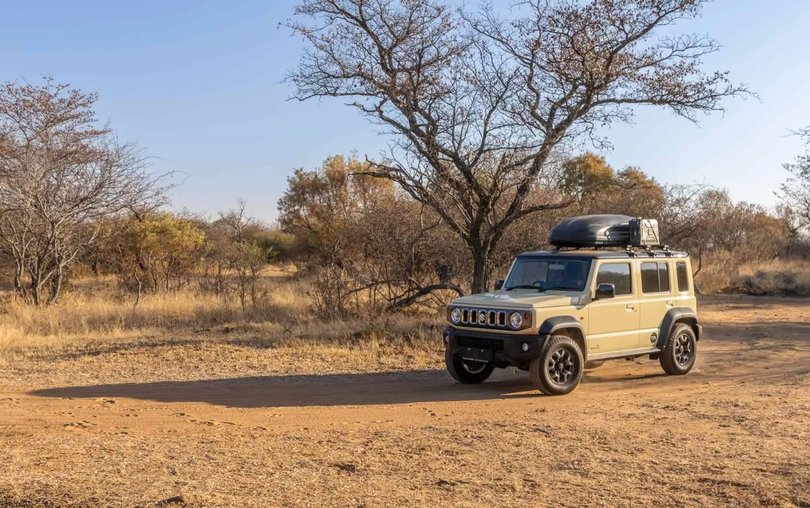 A Suzuki Jimny 5-door JC74 set up for touring, parked in the South African bushveld