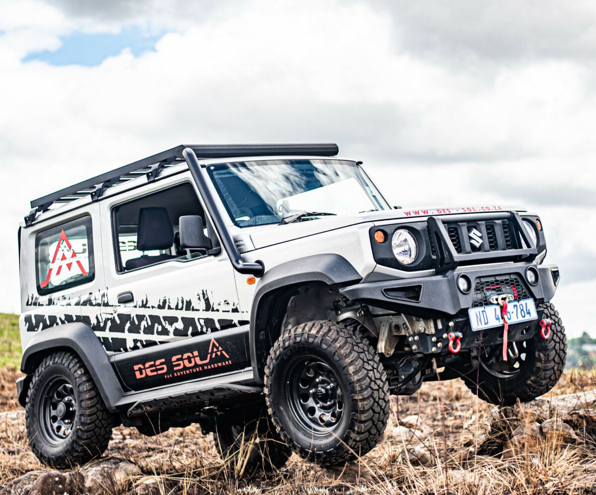 A lifted Suzuki Jimny on chunky all-terrain tyres flexing over rocky terrain, built by Des-Sol 4x4 Adventure Hardware