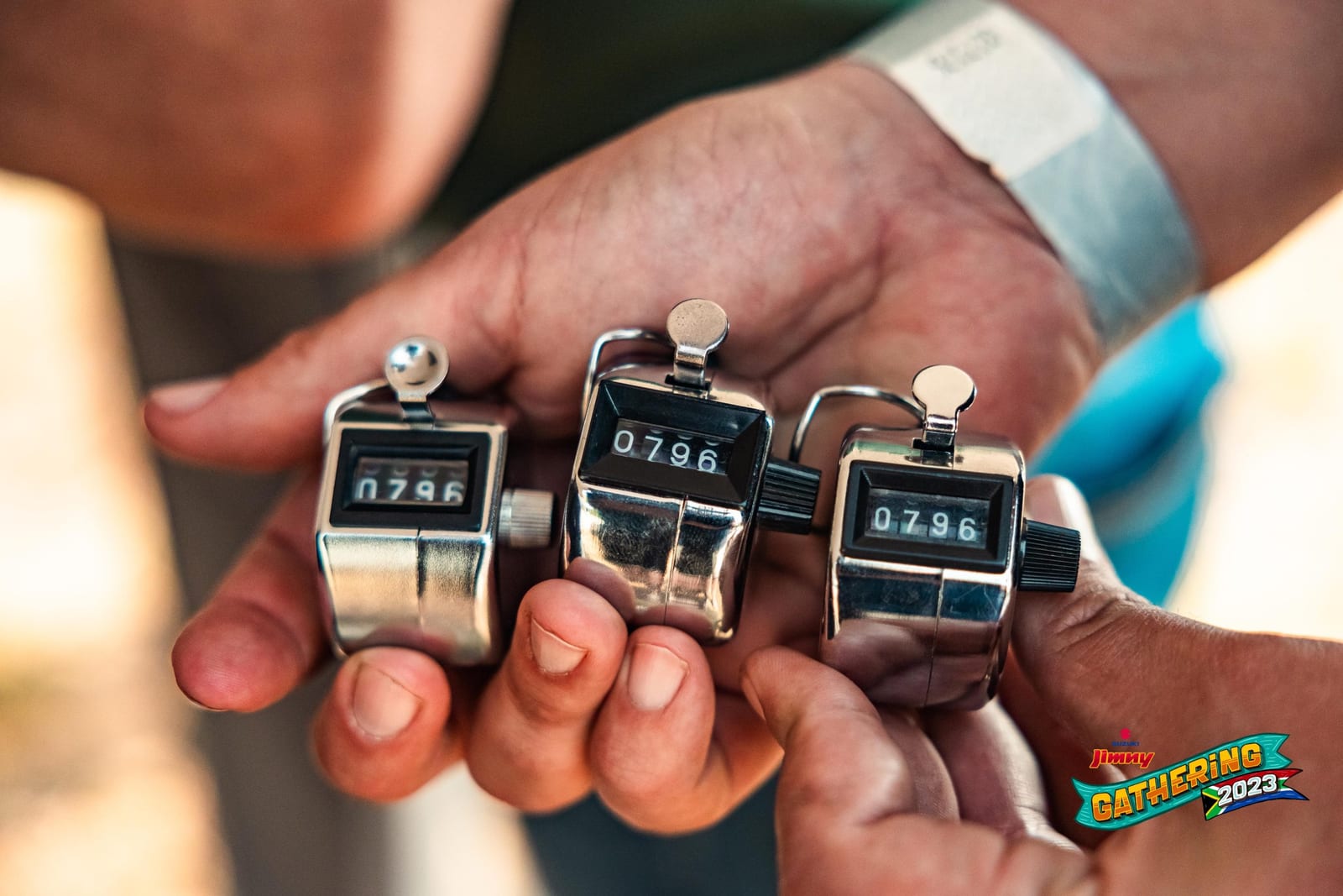 Three hand tally counters, all reading 0796, held out in a palm