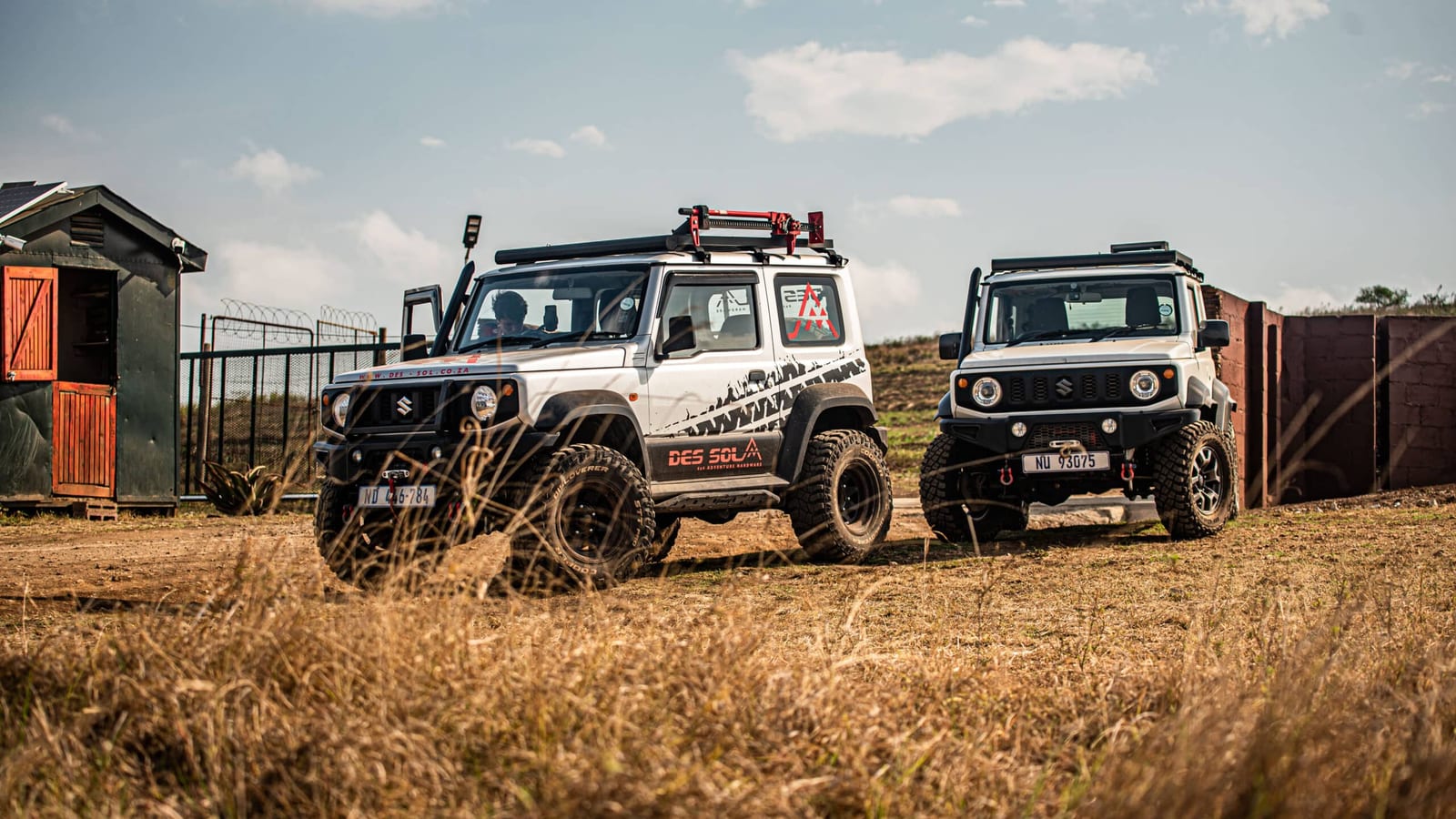 Two lifted current Suzuki Jimny 3-doors parked in a dry grass farm yard in KwaZulu-Natal, one in Des Sol livery