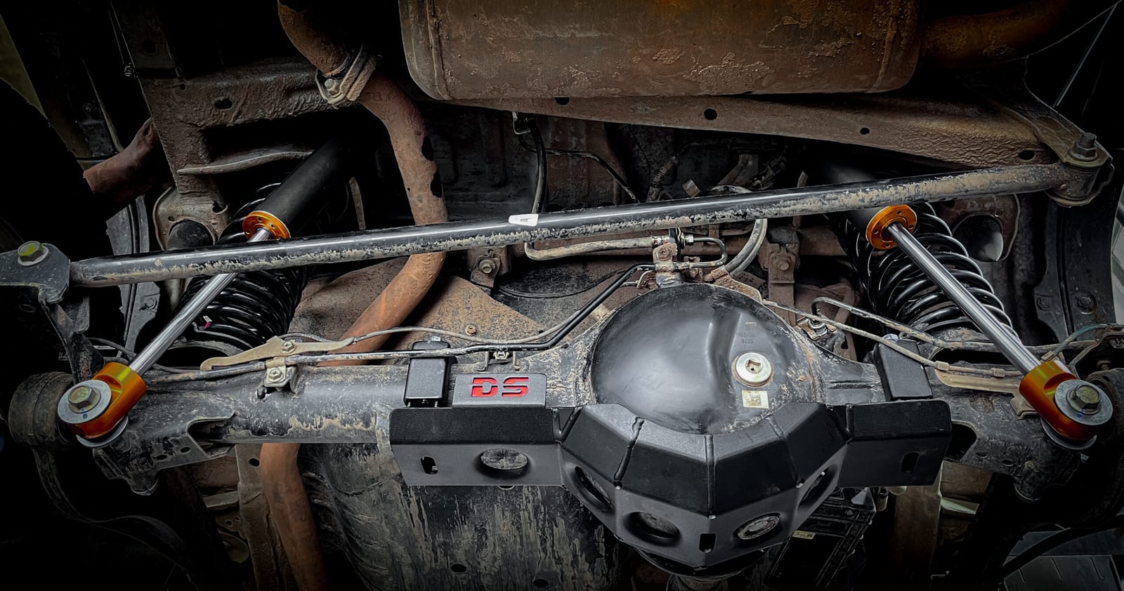 The underside of a Jimny showing the rear axle, an adjustable panhard bar, springs and shocks