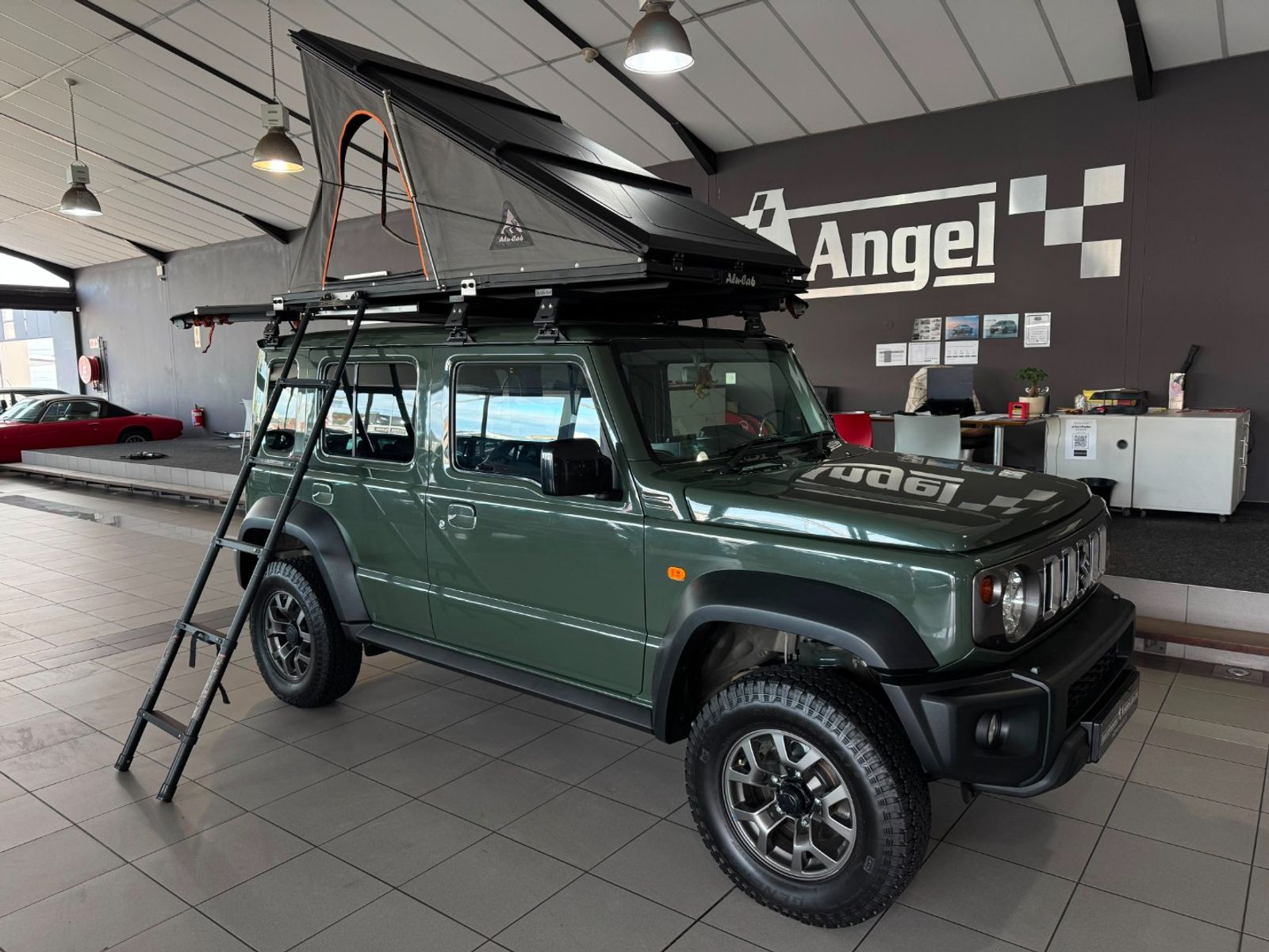 A green Suzuki Jimny 5-door with an Alu-Cab LT-50 deployed, listed for sale